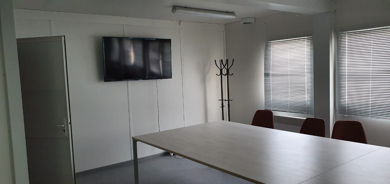 Office container interior — TV screen, meeting table, bright interior